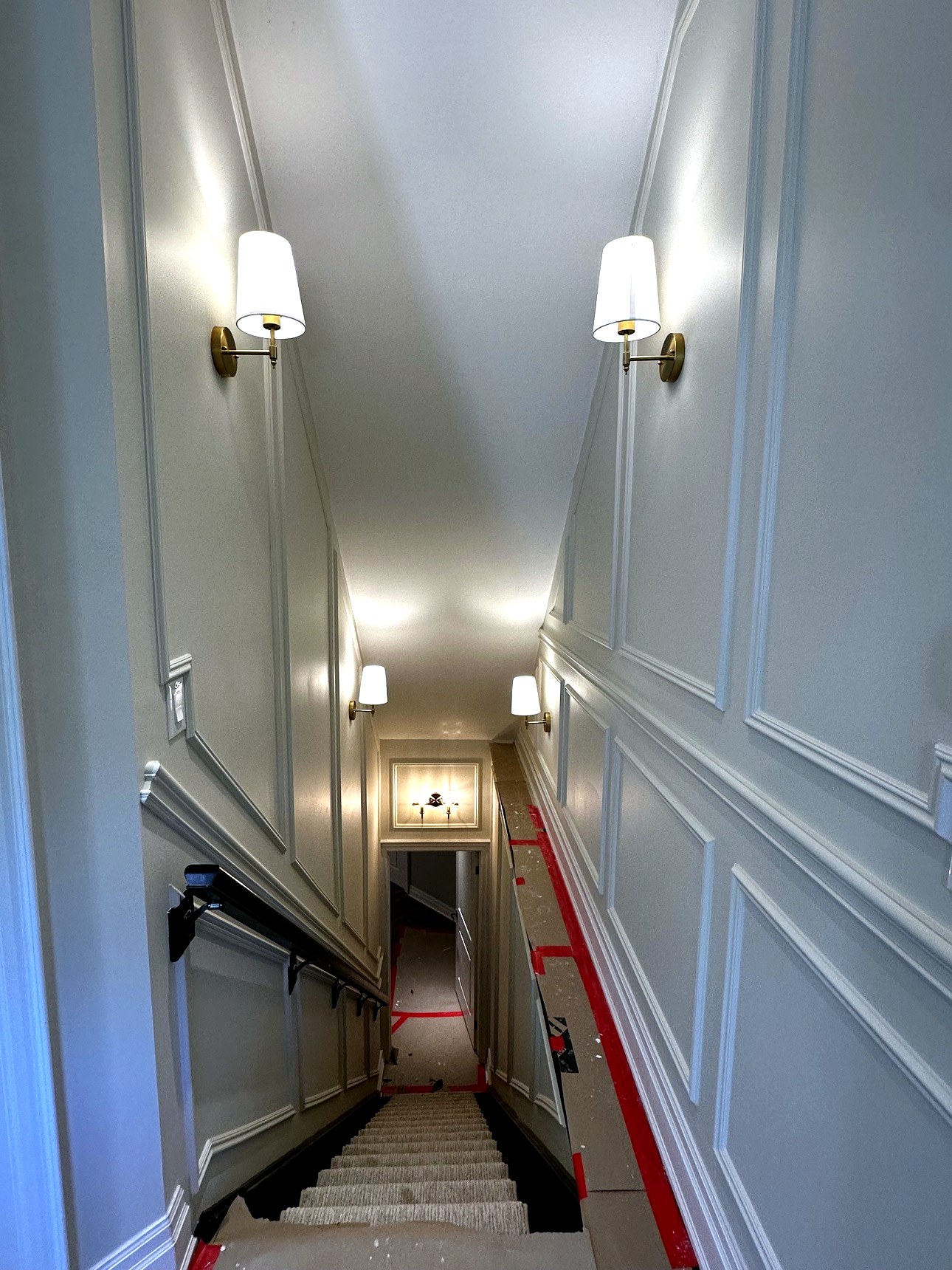 Stairwell with panel moulding accent walls and brass sconces
